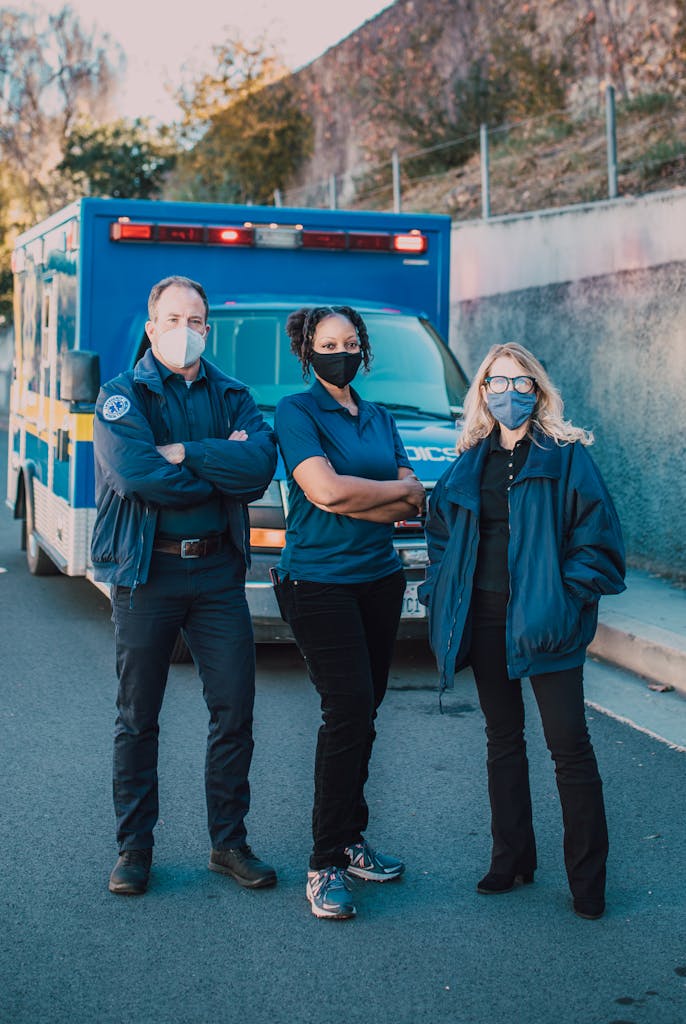 A diverse group of EMT professionals posing confidently in front of an ambulance, ready for action.